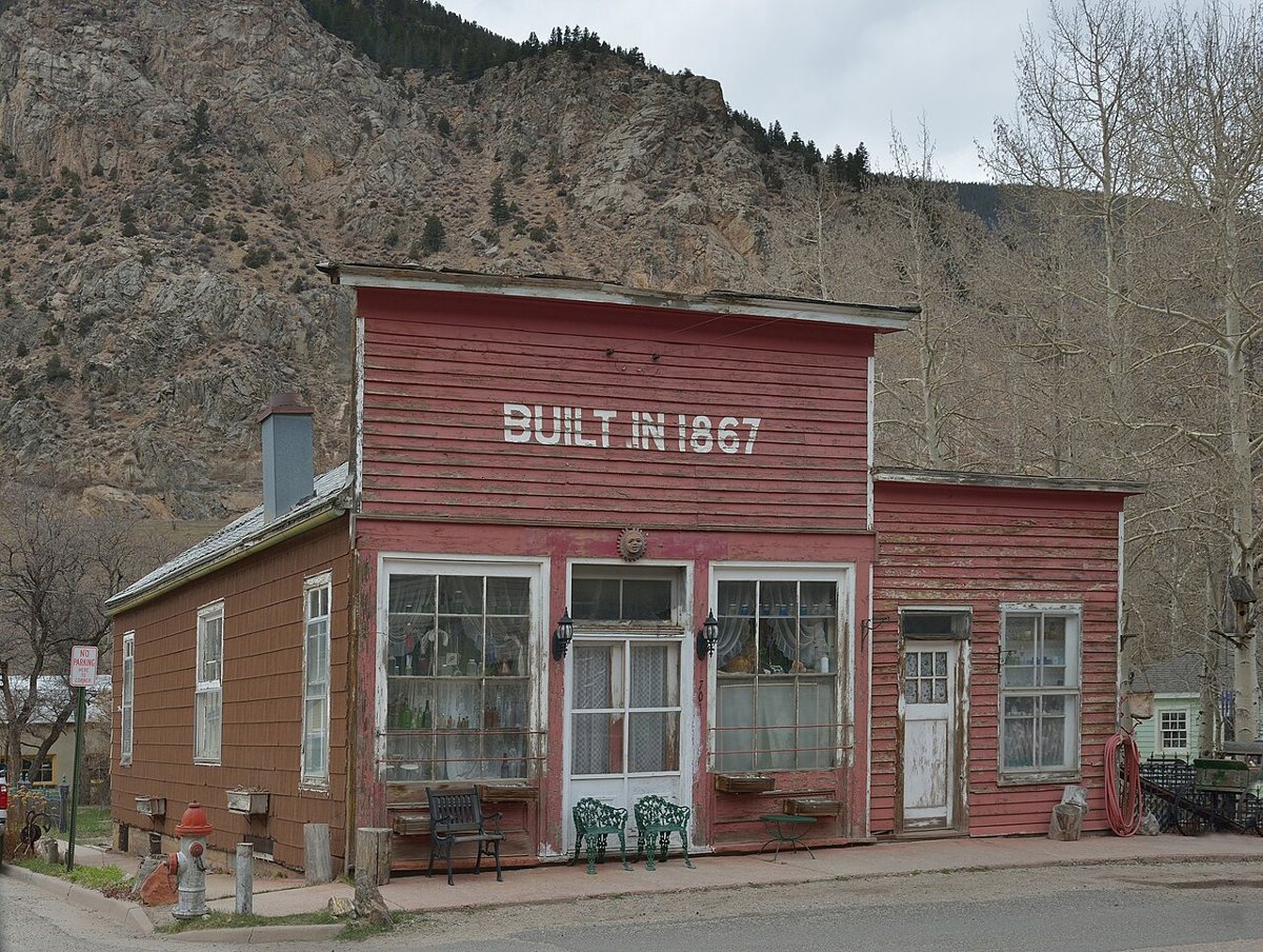 Historic Victorian storefronts on the main street of Georgetown, Colorado with mountains behind
