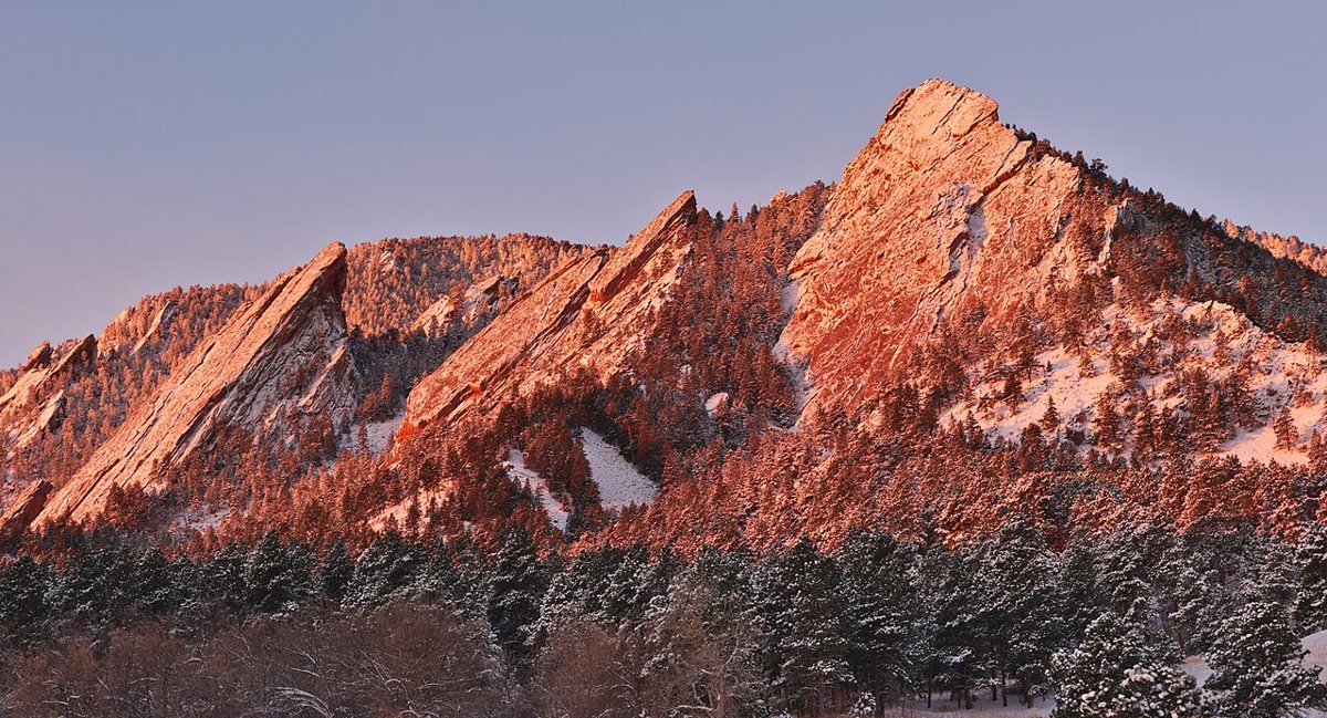 Boulder Colorado Flatirons rock formations rising above the city at sunset