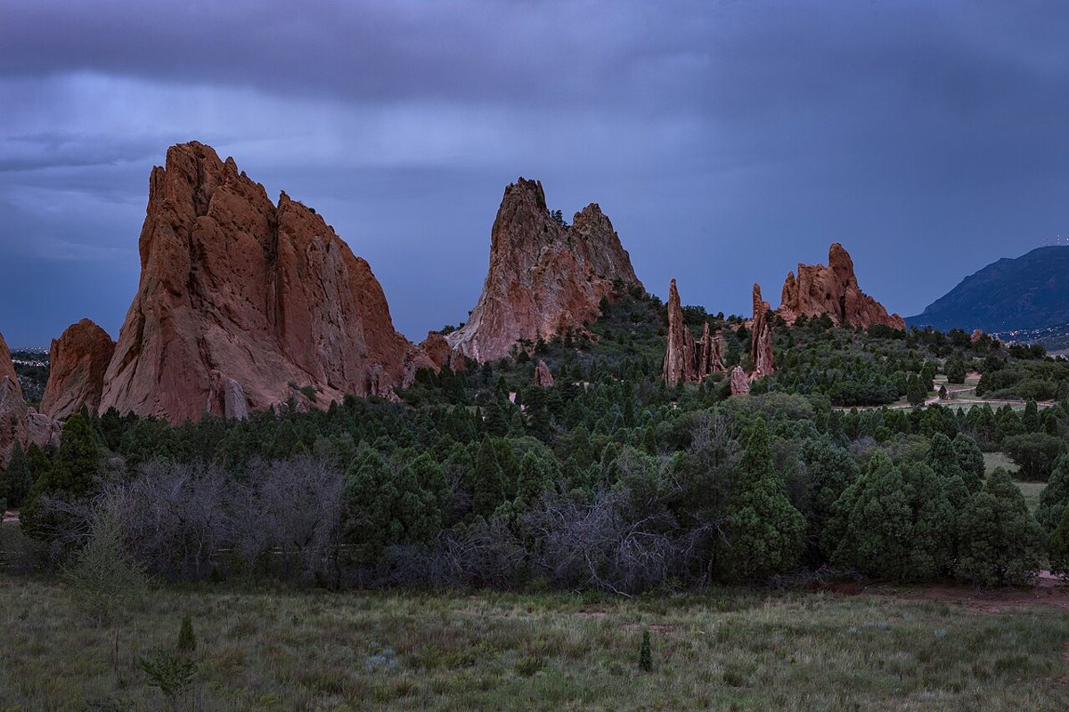 Red sandstone rock formations at Garden of the Gods with Pikes Peak in the distance