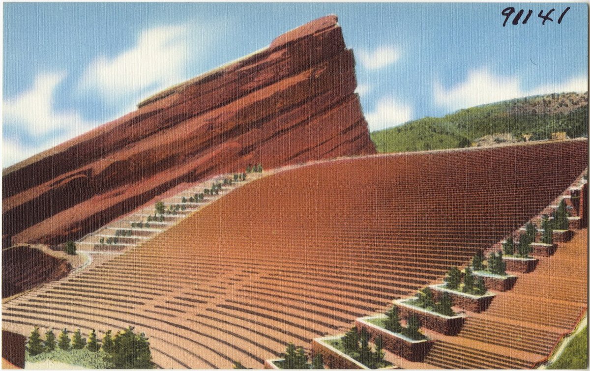 Red Rocks Amphitheatre Denver with massive sandstone formations flanking the concert stage at sunset with the plains stretching east